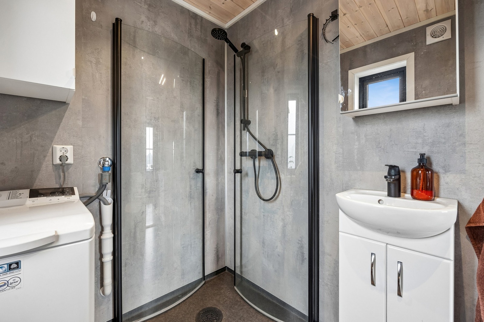 Badet er utstyrt med dusjhjørne, servantinnredning, toalett og opplegg for vaskemaskin. Galleribilde