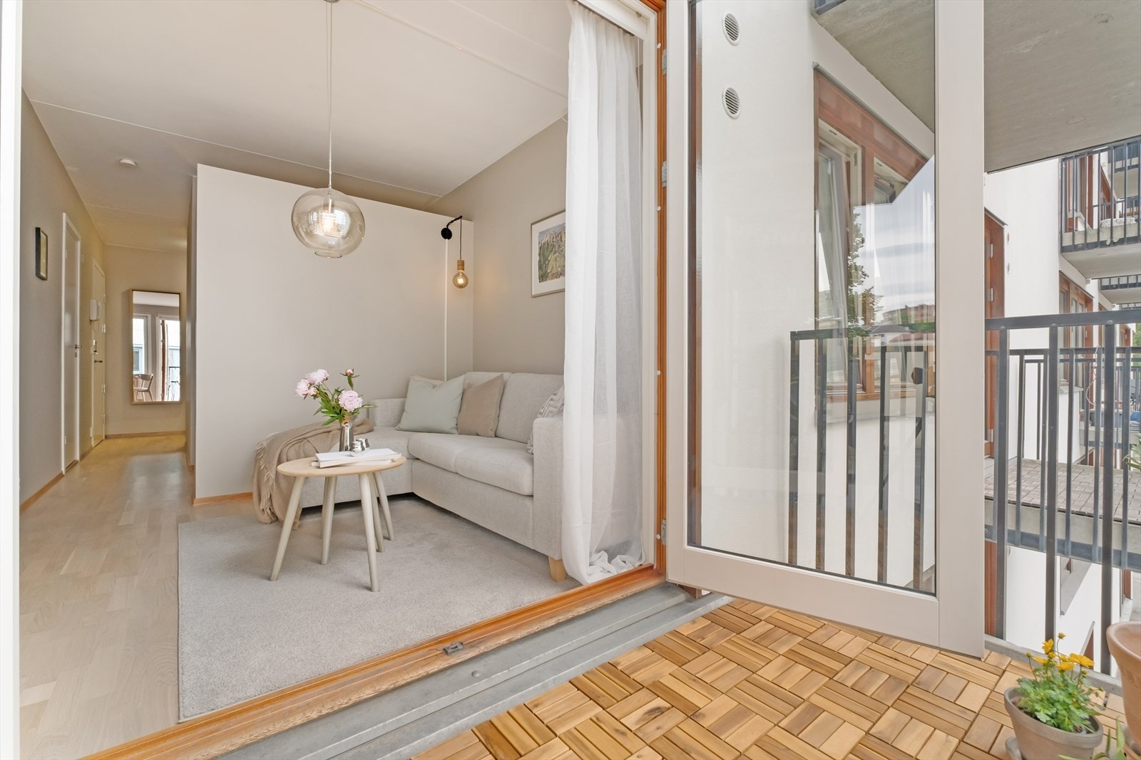 Store vinduer og balkongdør bidrar til å trekke uteplassen inn som en naturlig forlengelse av oppholdsrommet. Galleribilde