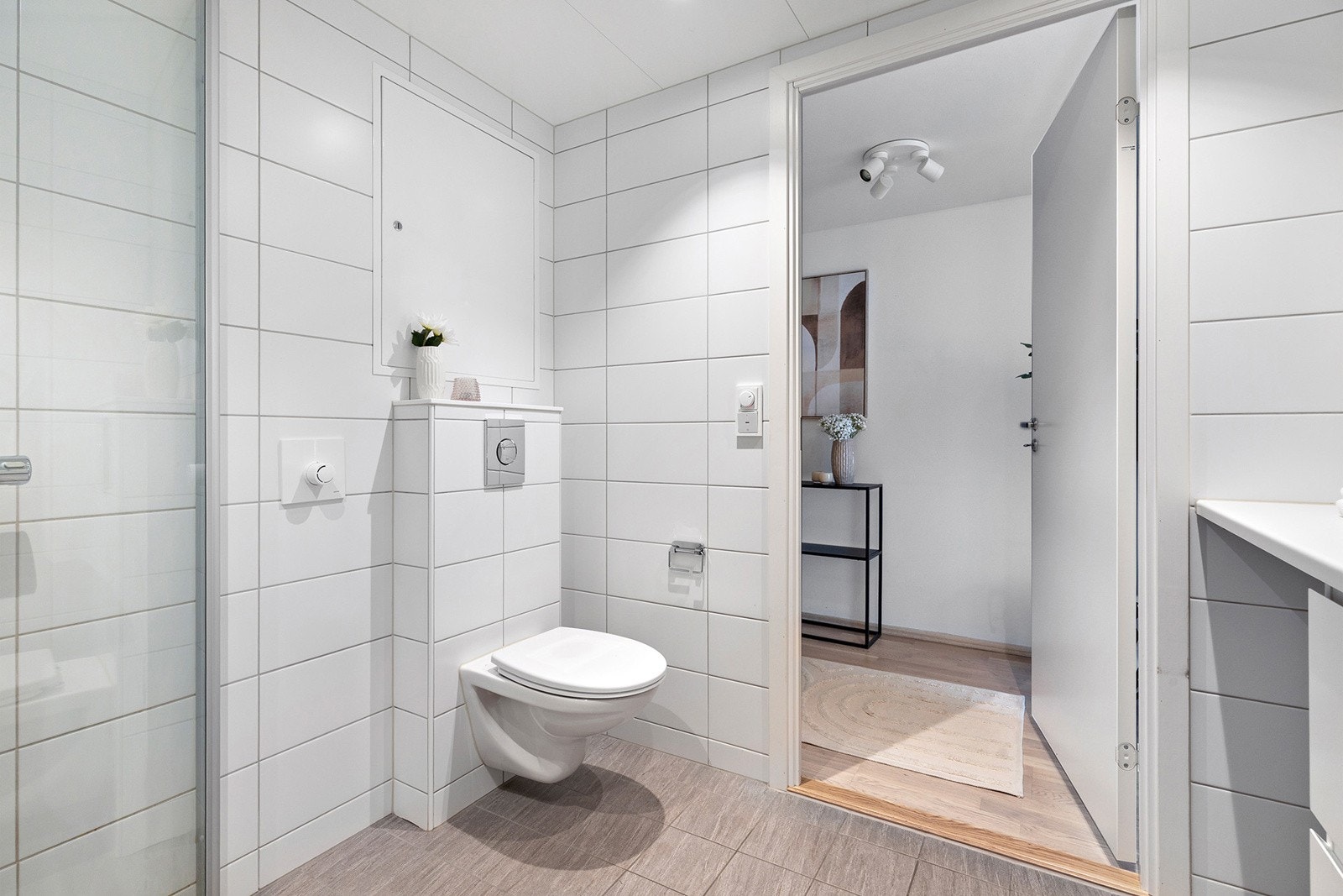 Badet har et romslig dusjhjørne med innfellbare glassdører og vegghengt toalett. Galleribilde