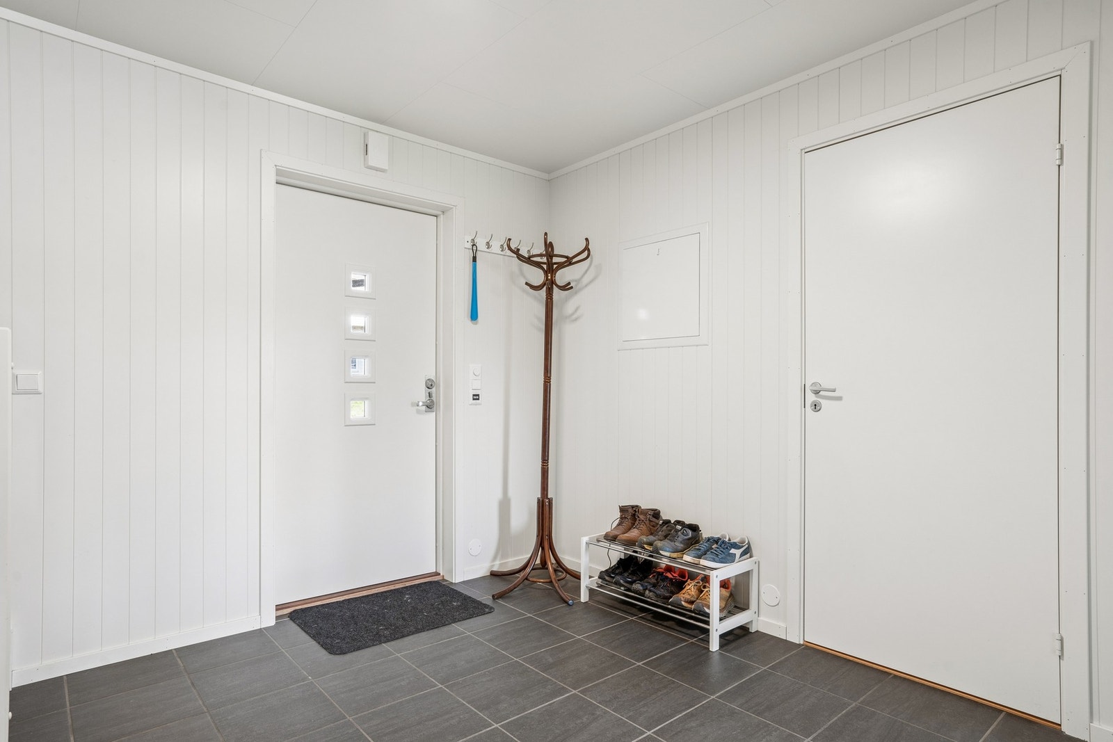 Romslig entré med flislagt gulv og plass til oppbevaring av yttertøy. Galleribilde