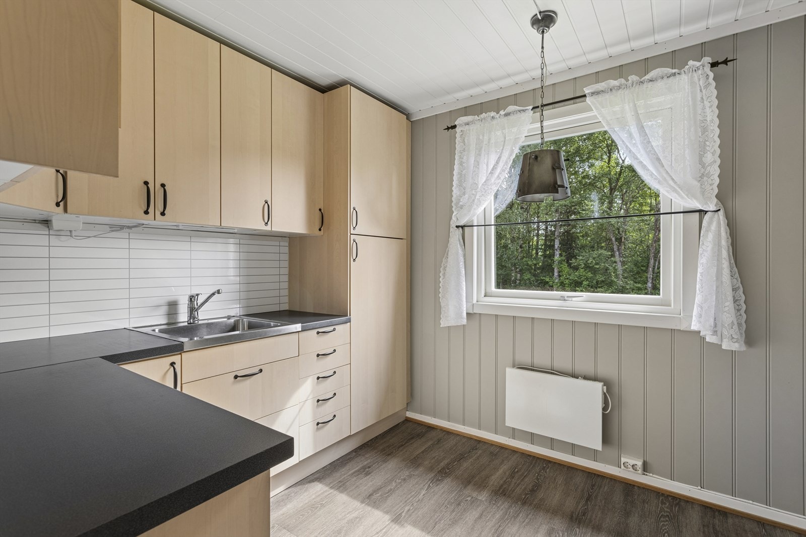 Kjøkkenet har en pen, takhøy innredning fra 2014 med lyse, slette fronter og laminatbenkeplate med nedfelt oppvaskkum. Vinylgulv lagt i 2020. Galleribilde