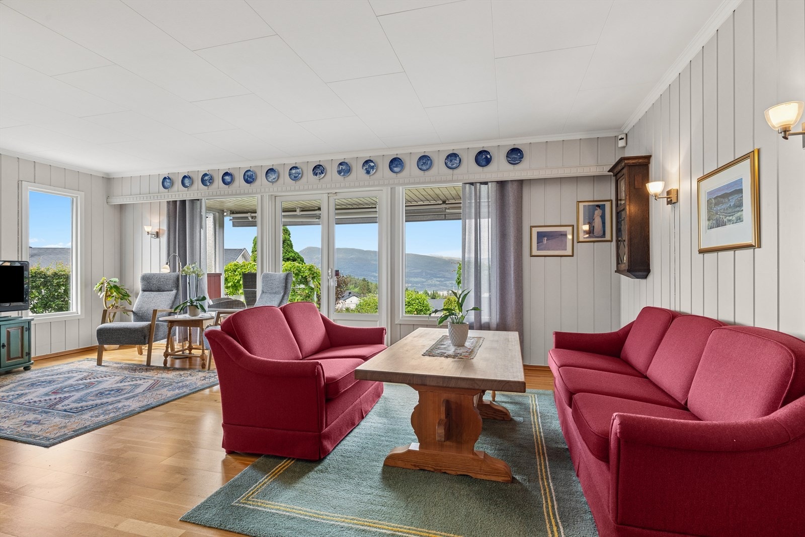 Den romslige stuen fremstår lys og luftig takket være store vindusflater som gir et flott lysinnslipp. Her er det god plass til både sofagruppe, spiseavdeling og annet ønsket møblement, noe som skaper et funksjonelt og innbydende oppholdsrom. Galleribilde