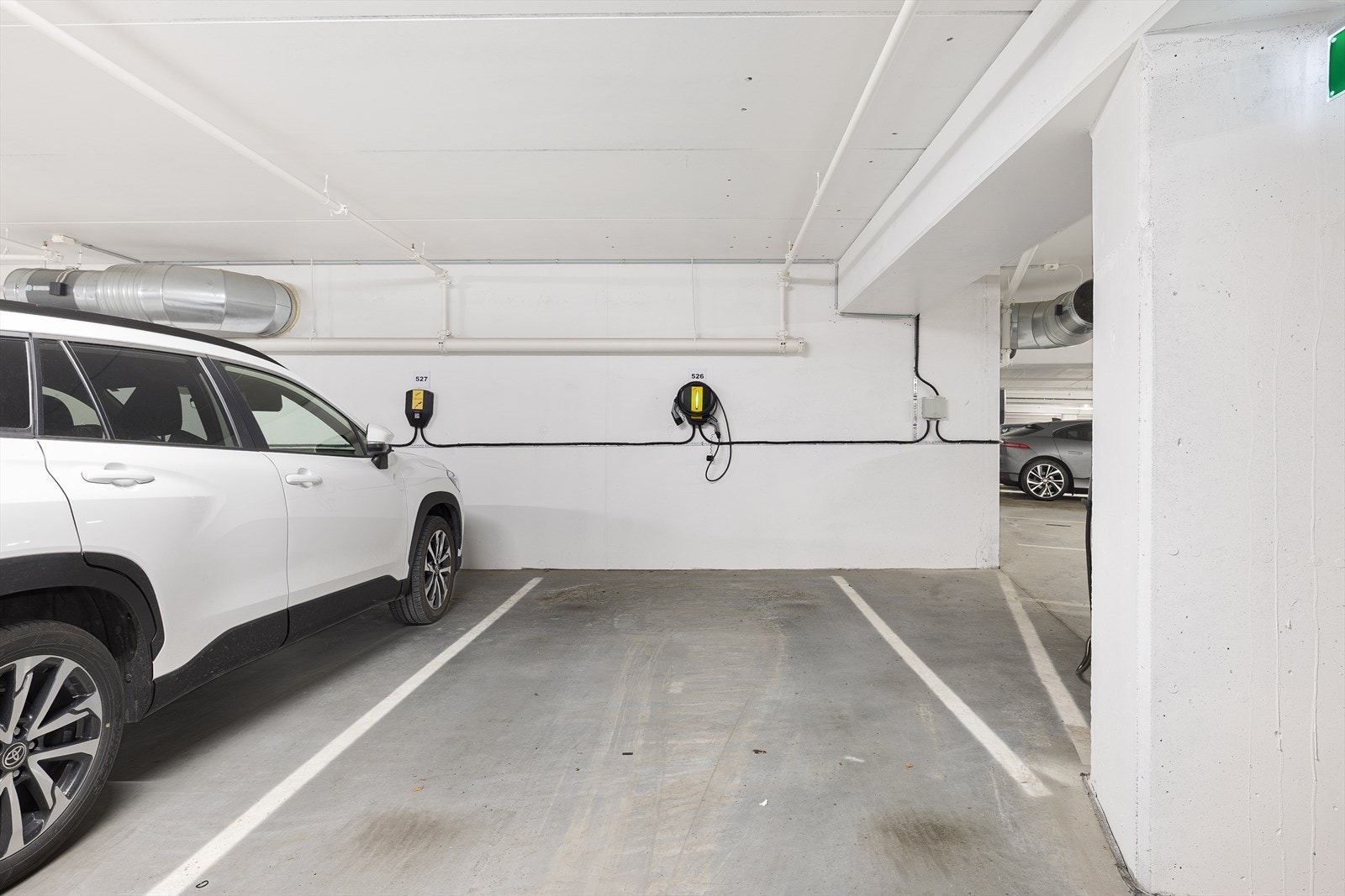 Leiligheten har bruksrett til en parkeringsplass i parkeringskjeller, hvor det er gjort klart for lading av elbil på alle plassene. Leie av garasjeplass er inkludert i de månedlige felleskostnadene. Galleribilde