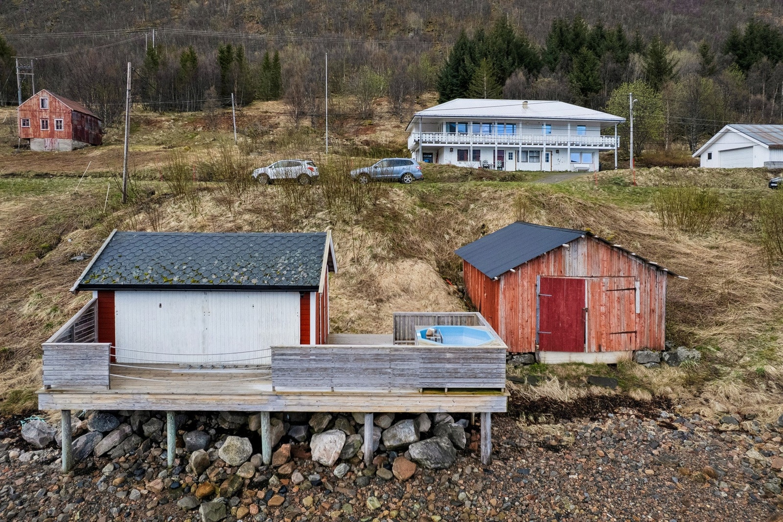 Nede ved fjorden ligger naust og en terrasse med badestamp. Galleribilde