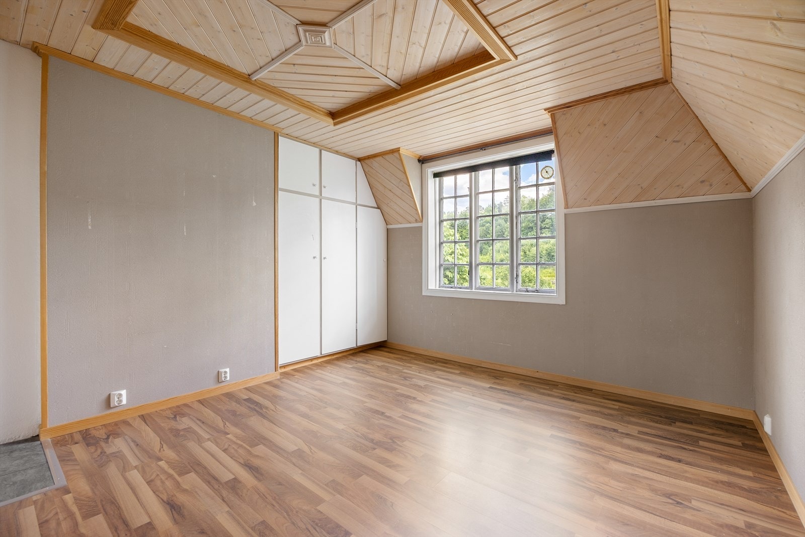 Ett av boligens seks soverom, med laminatgulv og panel i himling. Galleribilde