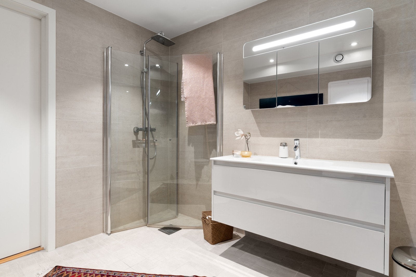 Badet er godt innredet med praktiske løsninger, flislagte overflater og med varmekabler i gulv.