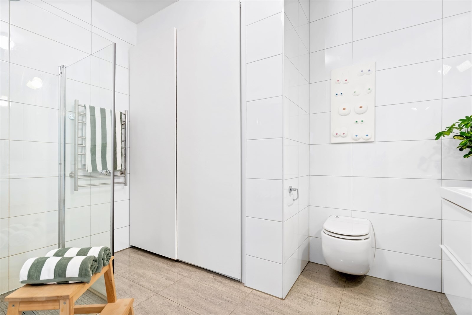 Stort, flislagt bad med varmekabler i gulvet samt opplegg for både vaskemaskin og tørketrommel. Galleribilde