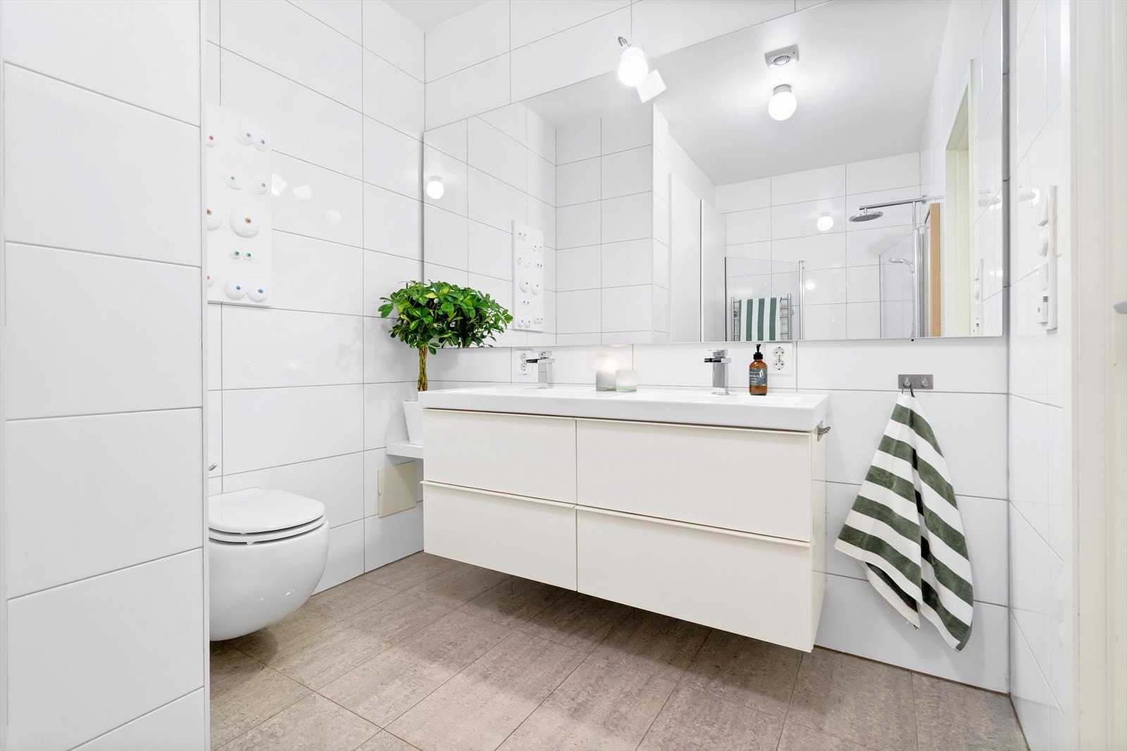Badet har vegghengt toalett, servantinnredning, hådkletørker og rikelig med oppbevaringsplass. Galleribilde