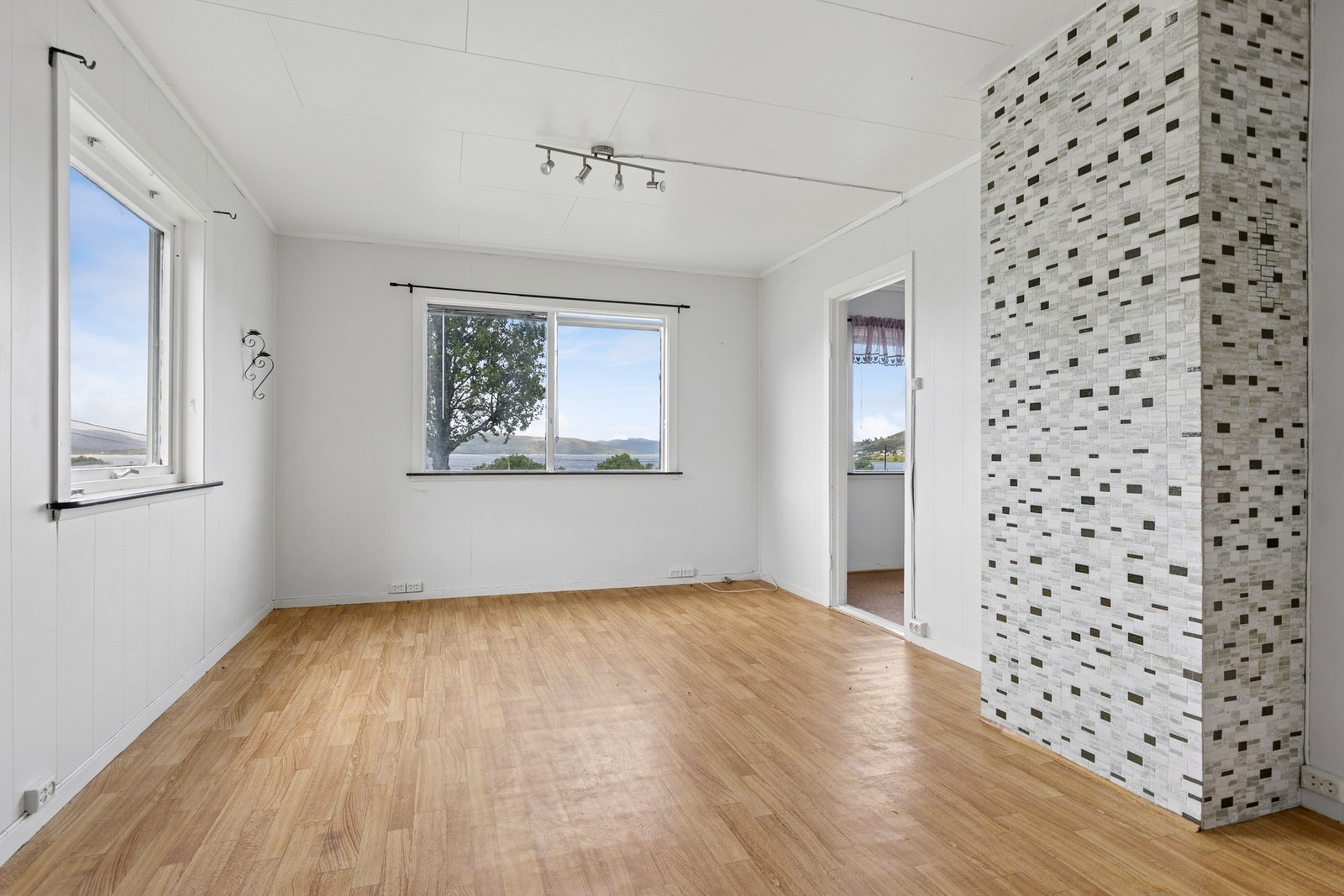 Rommet har en sentralt plassert mursteinspipe og flere vindusflater. Galleribilde