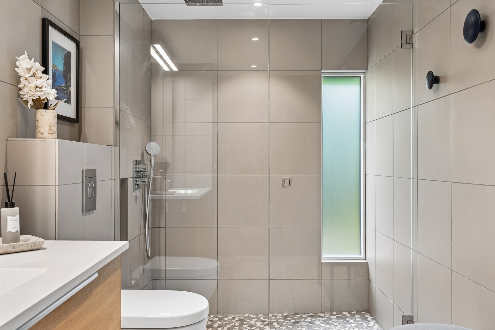 Badet har moderne innredning, dusjsone og vegghengt toalett. Downlights i himling. Galleribilde