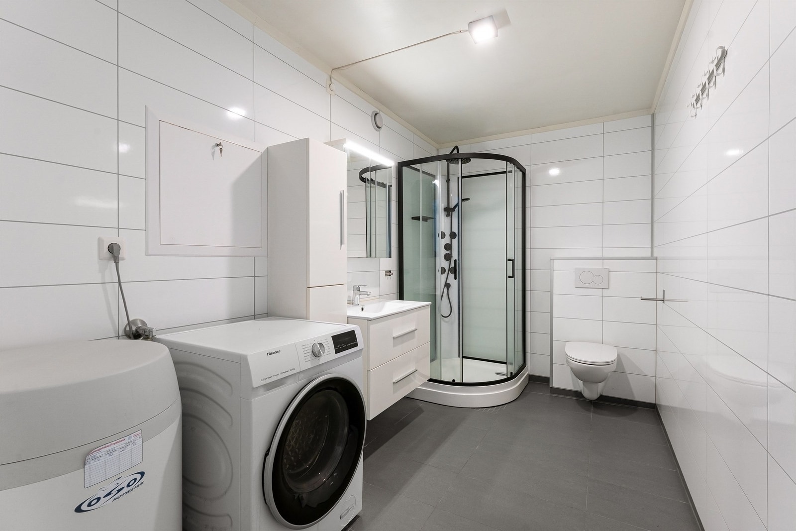 Badet har flislagt gulv med gulvvarme og opplegg for vaskemaskin. Galleribilde
