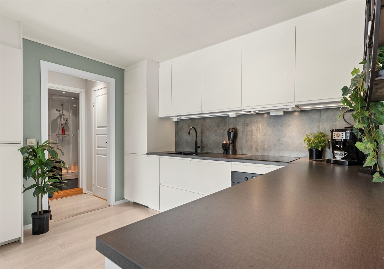 Kjøkkeninnredningen har hvite, glatte fronter og en mørk laminatbenkeplate med planlimt kum. Galleribilde