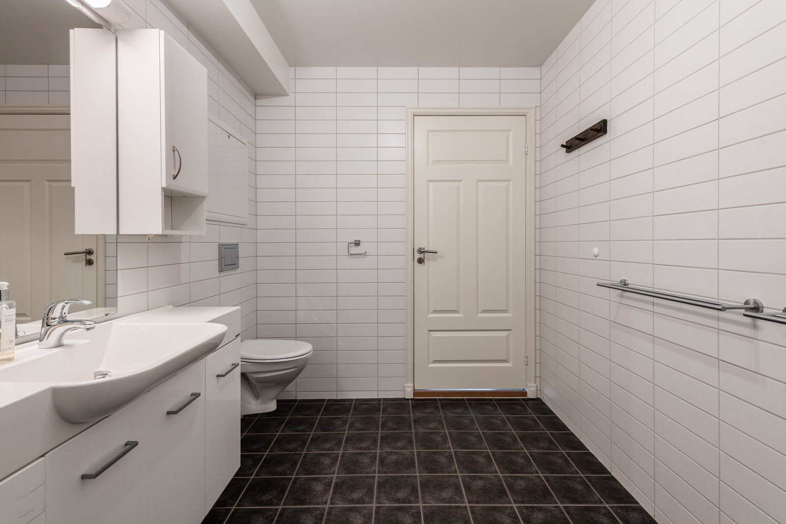 Badet har servantinnredning, håndvask, veggtoalett og dusj med dører/vegger i glass. Galleribilde