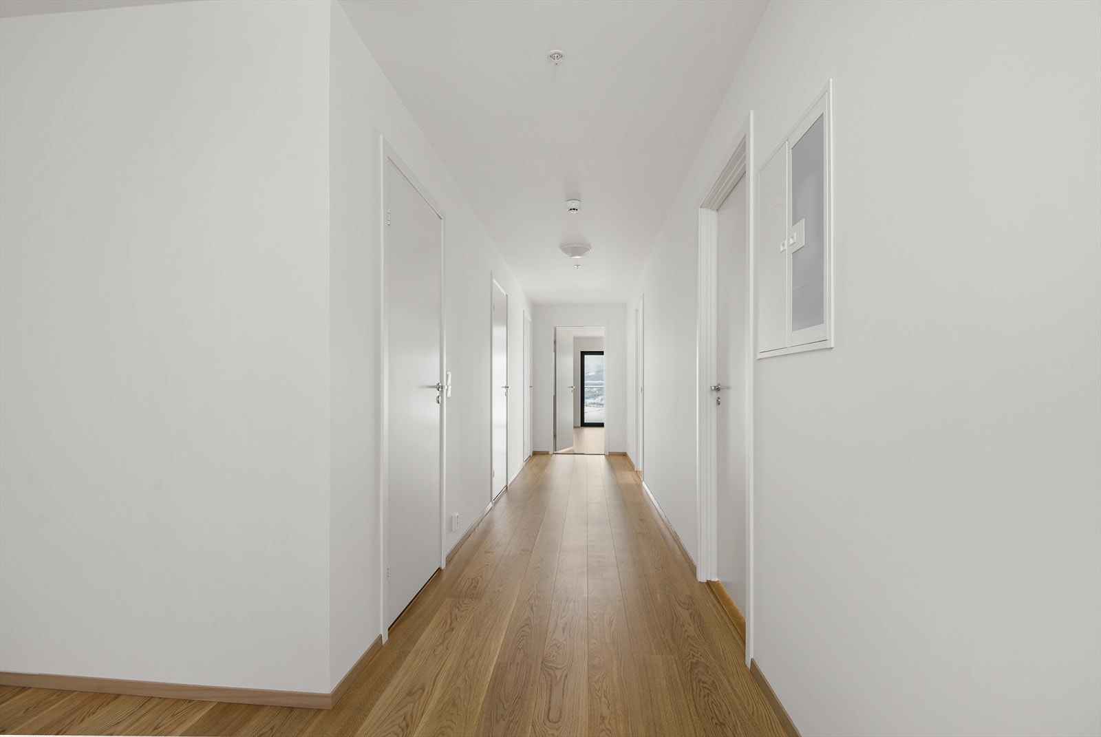 Hall med 3 soverom på høyre side og 2 flislagte bad og et teknisk rom på vestre side. Galleribilde