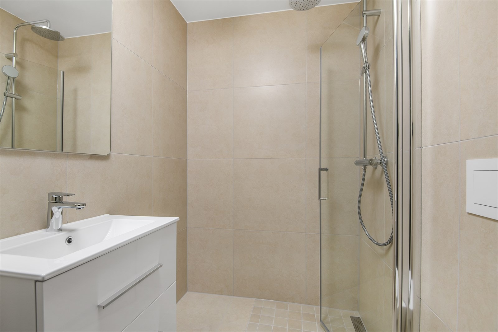 Det minste badet er også flislagt med beige fliser på gulv og vegg, men har hvit baderomsinredning Galleribilde
