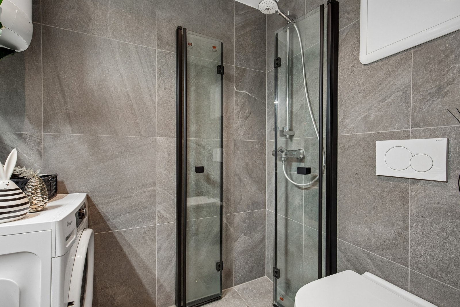 Badet er utstyrt med bla. servant, veggmontert toalett, dusjvegger/hjørne og opplegg for vaskemaskin. Galleribilde