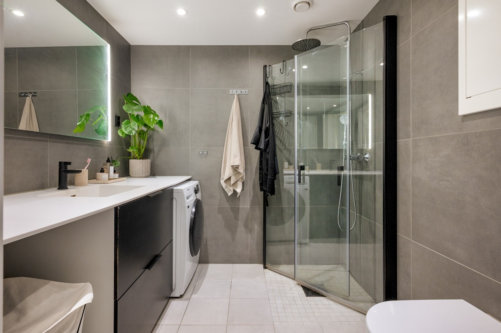 Badet er utstyrt med vegghengt klosett, enkel servant, downlights i himling, opplegg for vaskemaskin samt dusjhjørne med foldbare glassdører for maksimal arealutnyttelse. Galleribilde