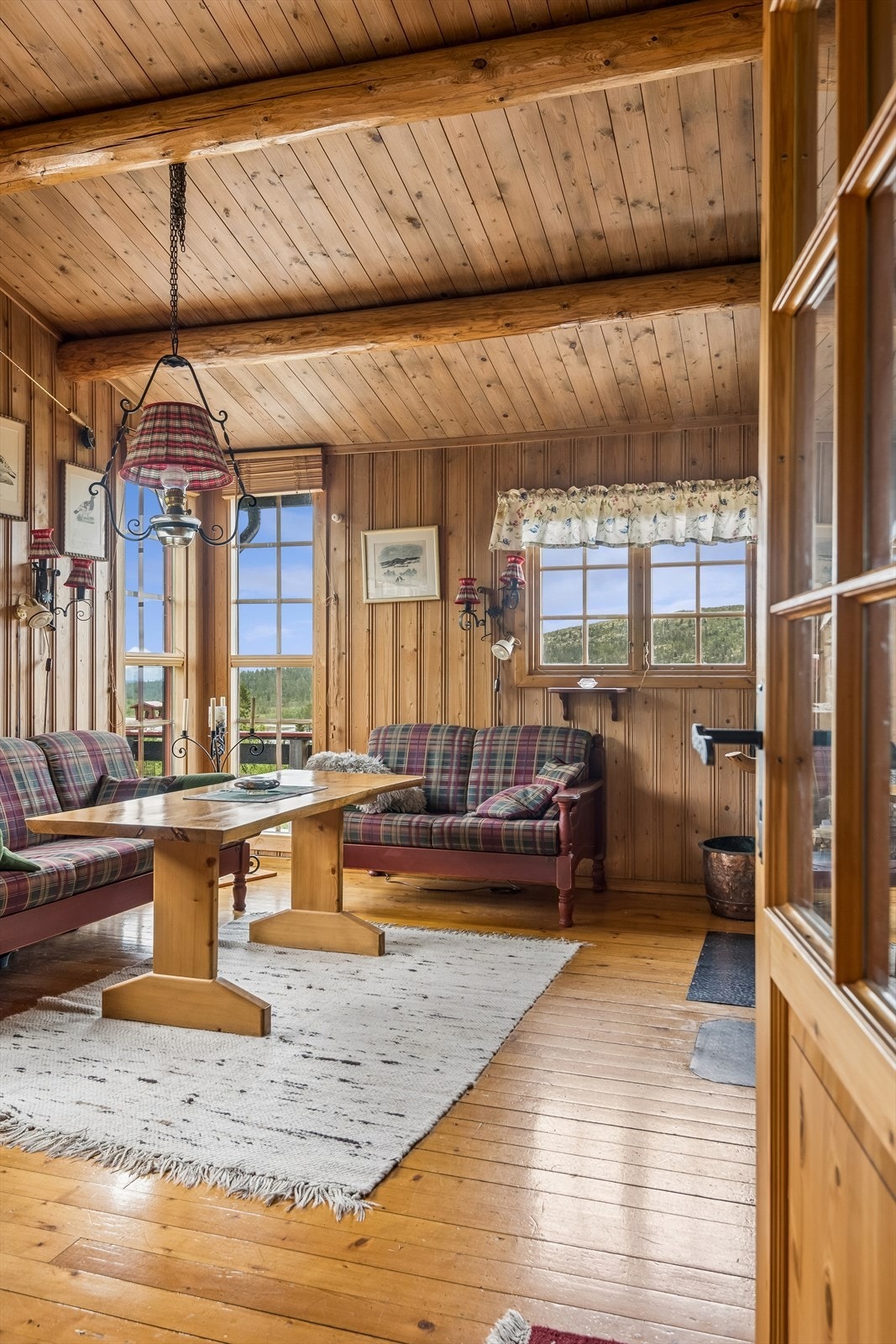 Synlige takåser og panelkledde vegger gir stuen en klassisk hyttestemning. Galleribilde