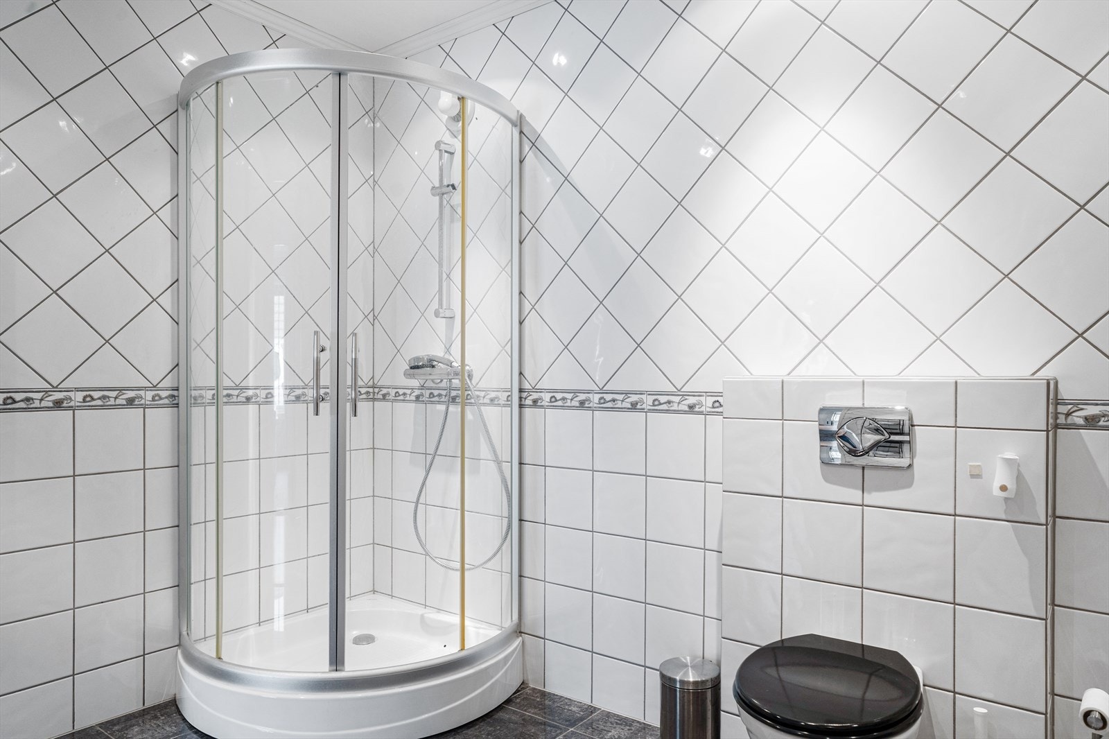 Badet er innredet med dusjkabinett, vegghengt toalett, speilskap, baderomsinnredning med enkel servant og skuffer til oppbevaring Galleribilde