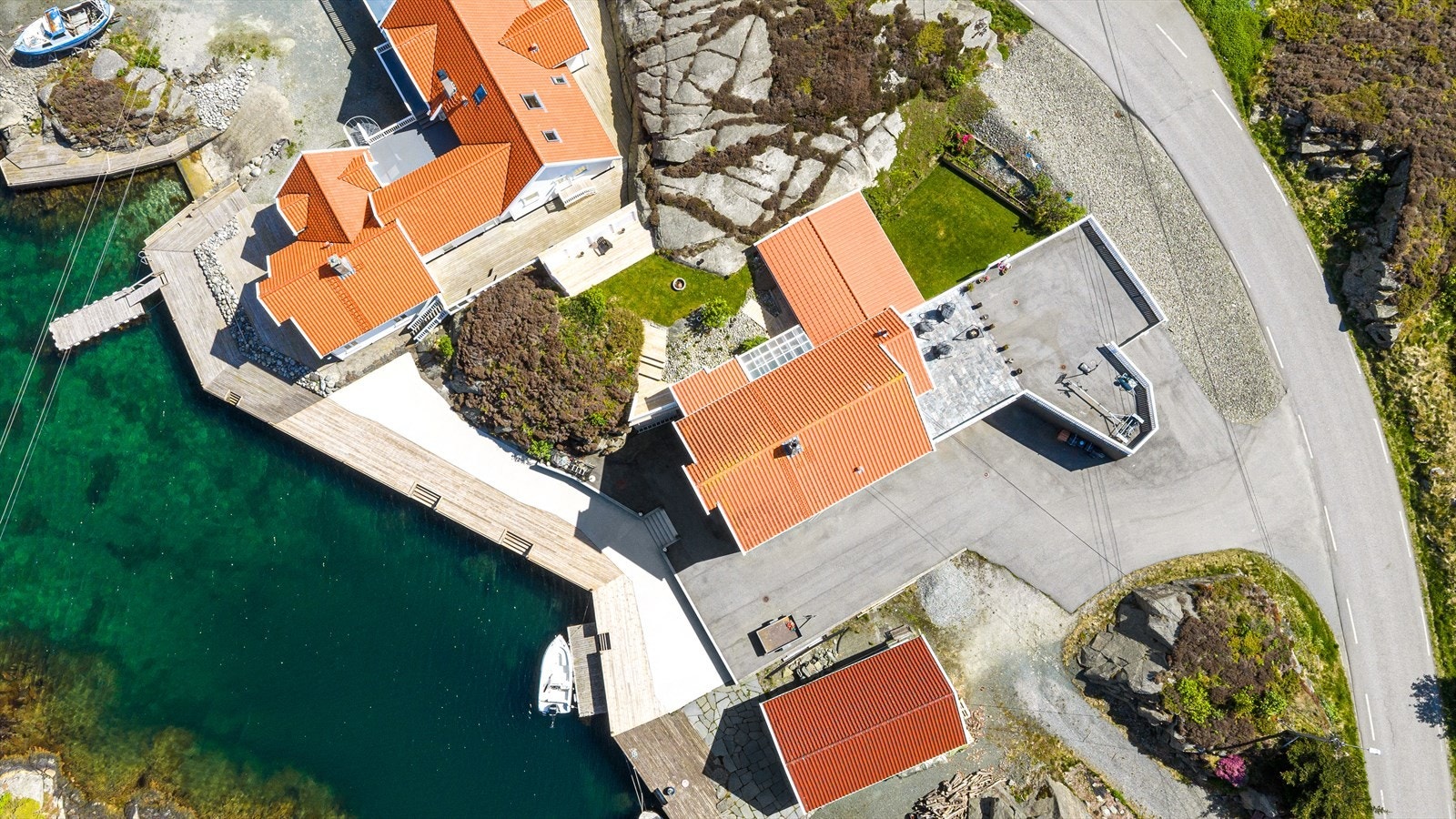 Tomten er pent opparbeidet med stor med hele ca 32 meter brygge/kai, romslig asfaltert gårdsplass, steinbelagt terrasse, terrasser i tre, bedd, kulesteiner og plener Galleribilde