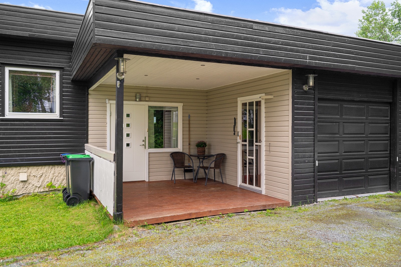 Takoverbygd inngangsparti med terrasse, downlights og dør inn til garasjen, samt utebelysning med sensor.