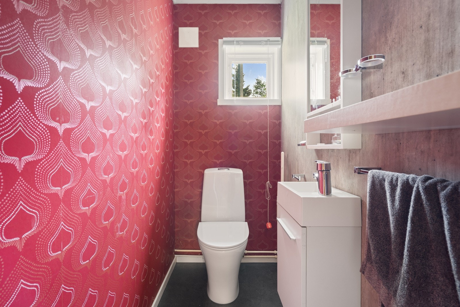 Toalettrom med wc og baderomsinnredning med servant.