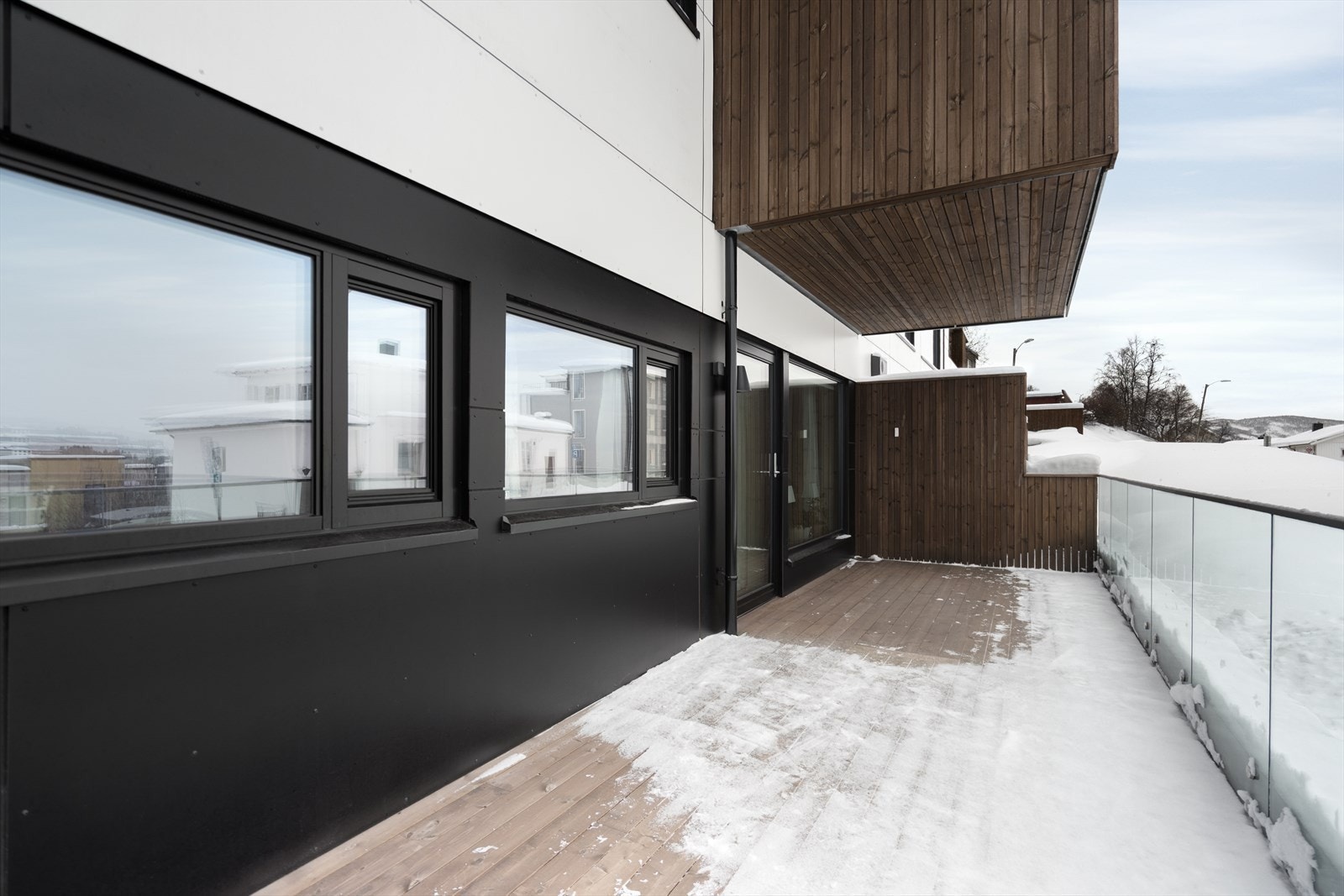 Verandaen har glassrekkverk som gir et moderne uttrykk og godt lysinnslipp, samt en praktisk skillevegg som skjermer mot innsyn og gir le. Galleribilde