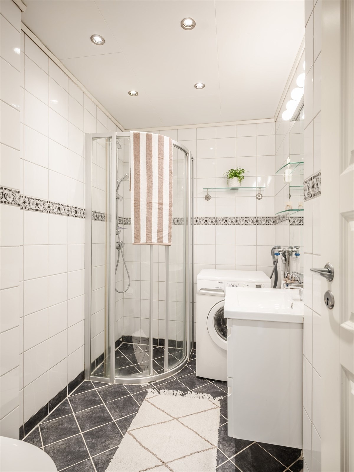 Øvrig innredning på badet består av dusjhjørne, wc og opplegg for vaskemaskin. Downlights i himling. Galleribilde