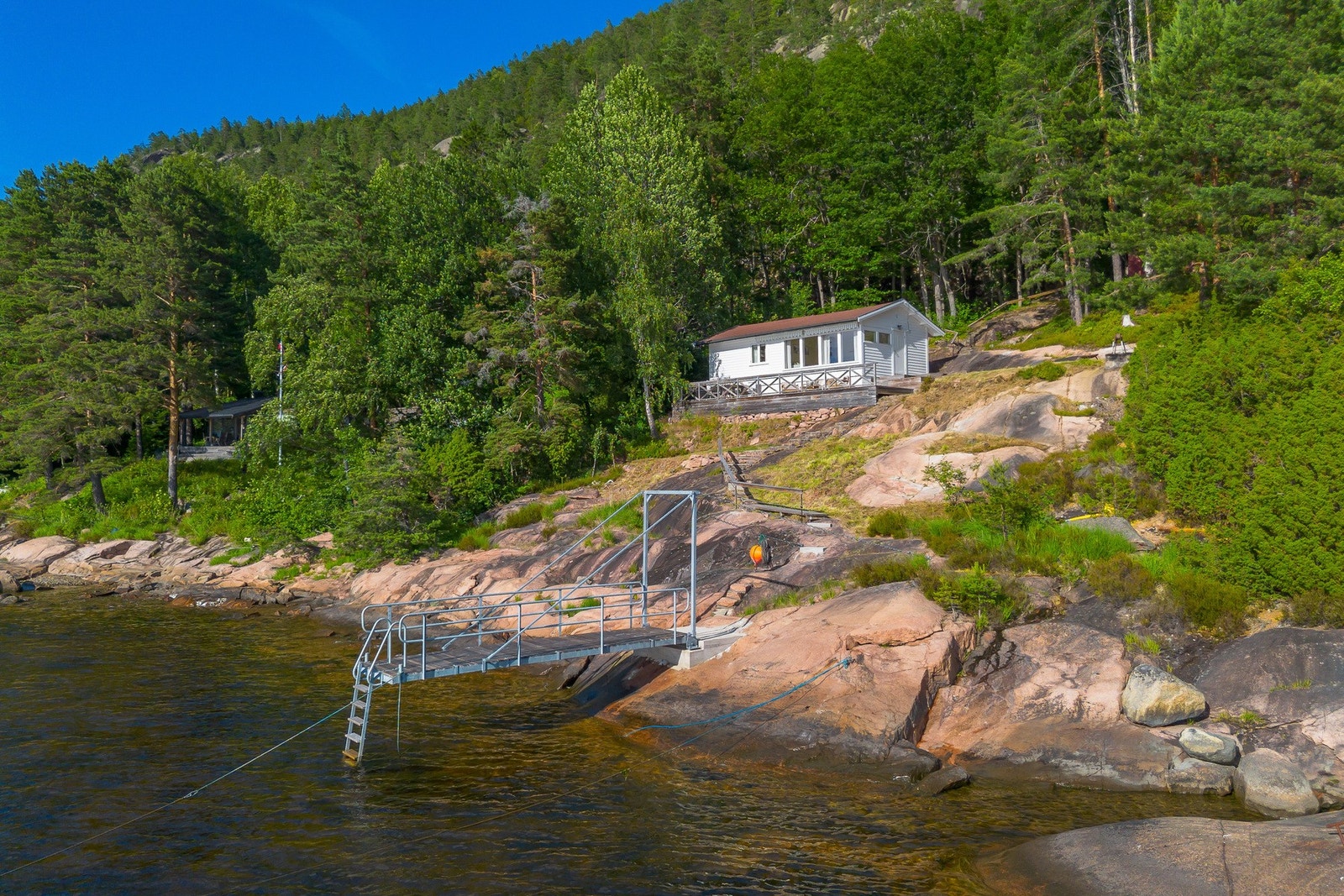 Terrassen har dekke og rekkverk i tre, god plass til møbler og en trapp opp til inngangen på siden av hytta. Galleribilde