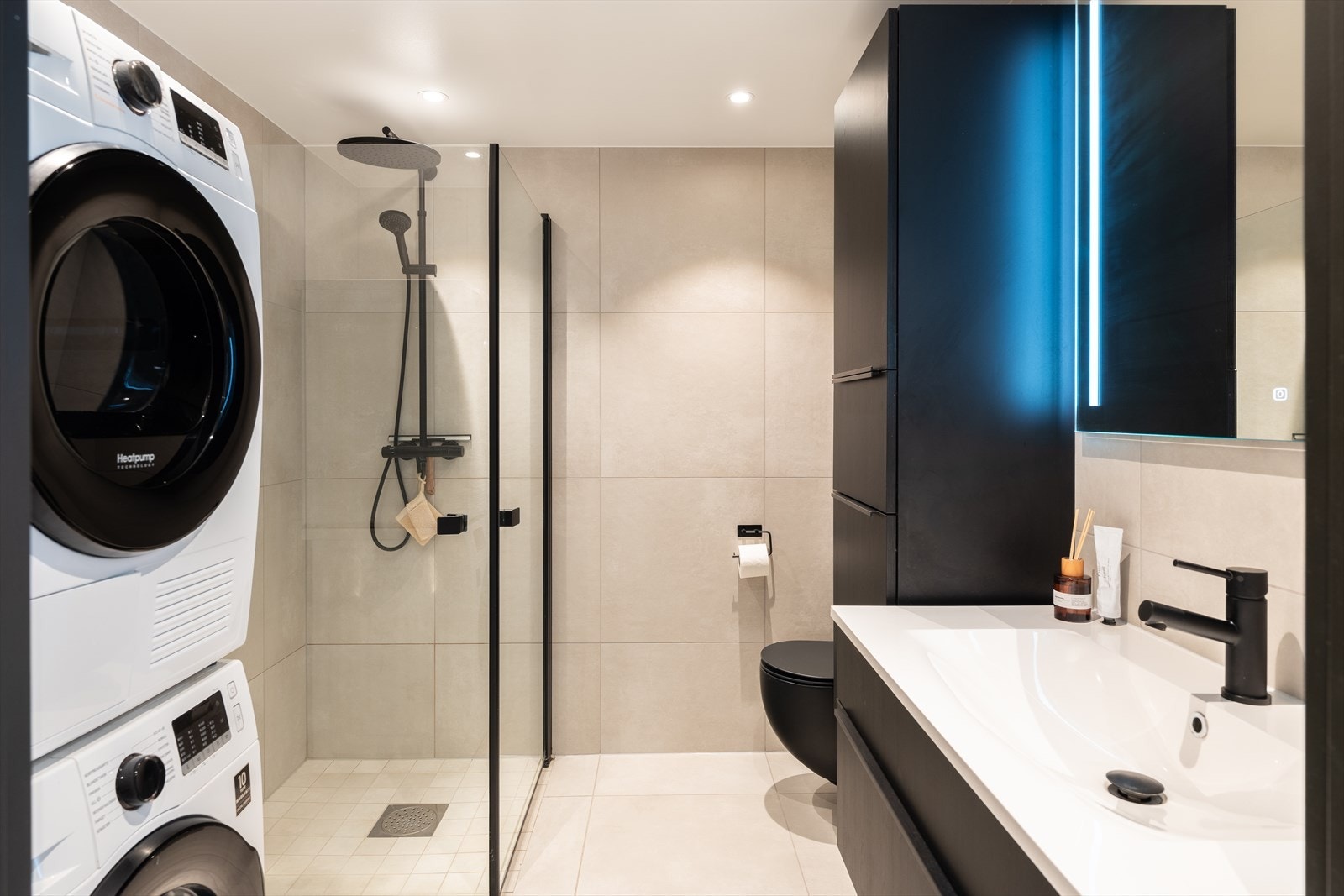Badet innehar en rekke moderne fasiliteter som innfellbare dusjdører, regndusj, opplegg for vaskemaskin, gulvvarme, vegghengt toalett og downlights i himling. Galleribilde