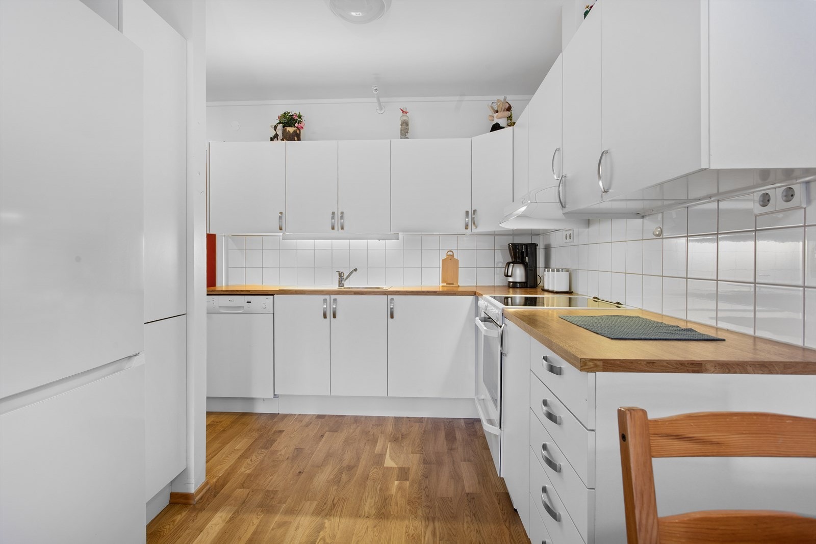 Kjøkken med hvite slette fronter. Fliser over benk. Enkelt å holde rent og pent. Galleribilde