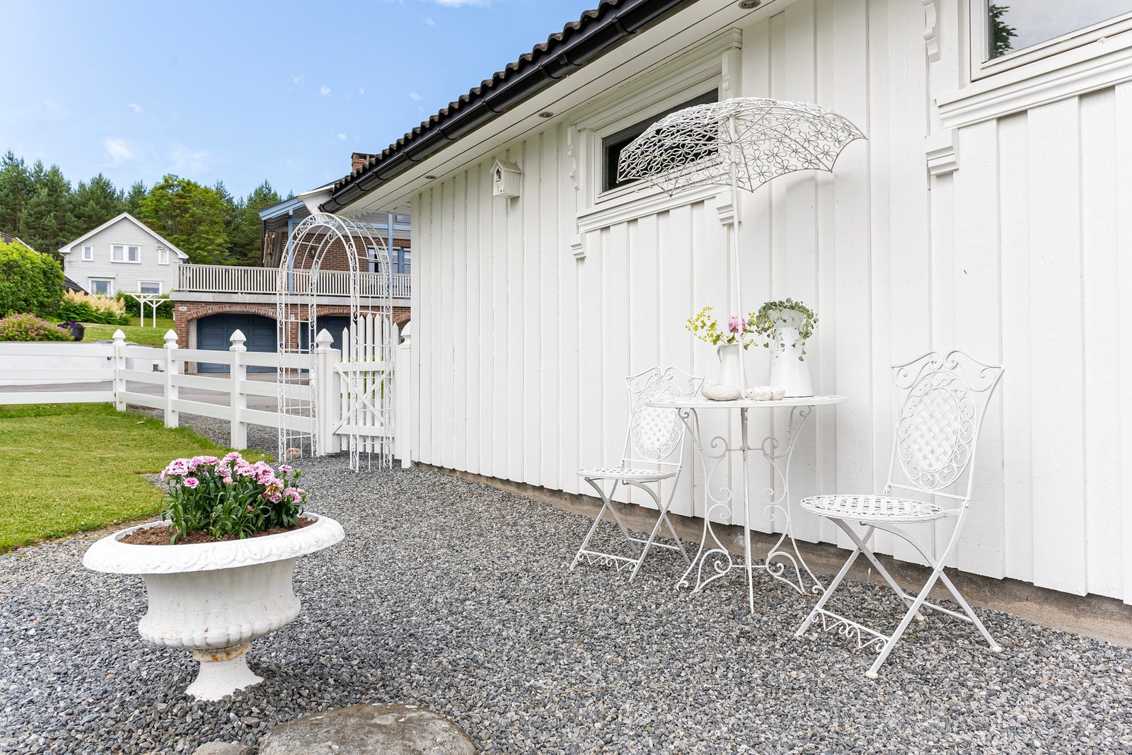 Gårdplass og adkomst er belagt med grus, og her er det laget en koselig uteplass ved garasjen. Galleribilde