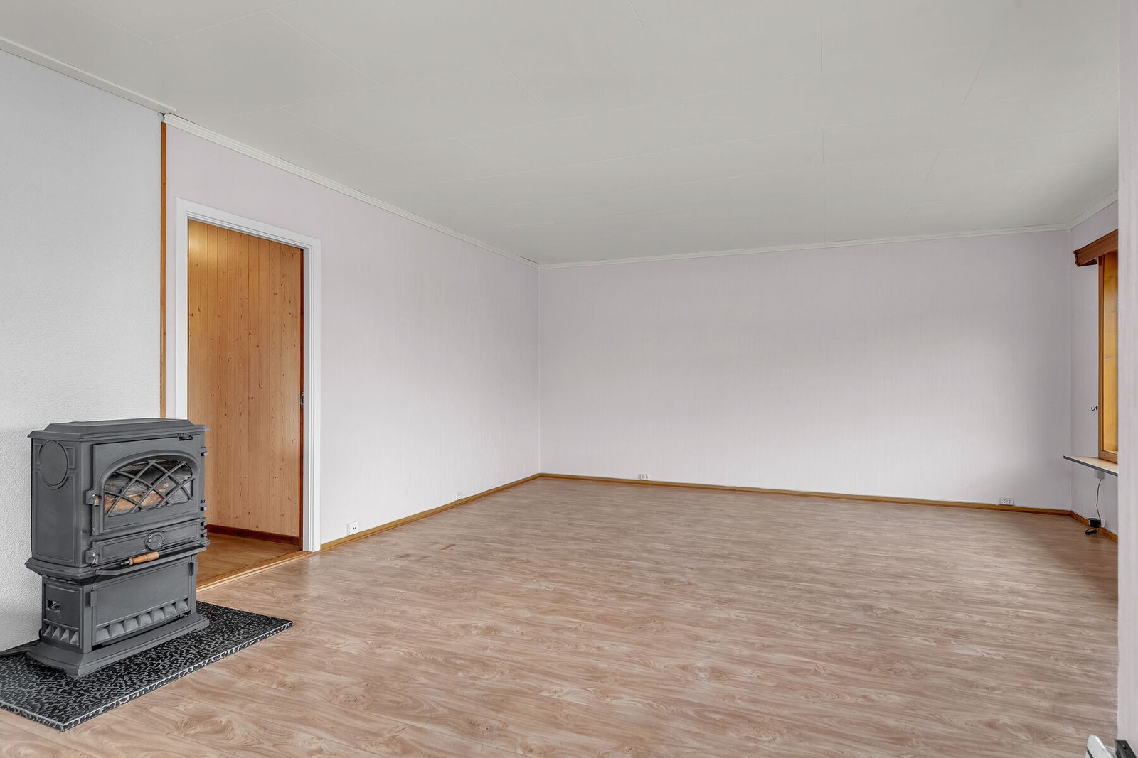Overflatene i stuen består av malt strietapet på vegger og laminat på gulv. Galleribilde
