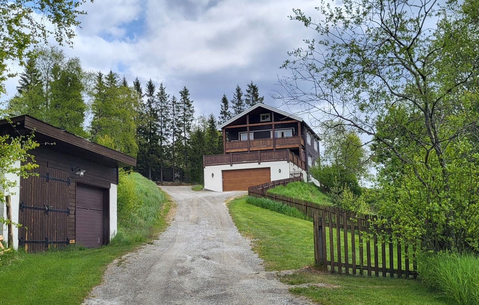 Huset sett fra E136. Dobbel garasje ved veien og dobbel garasje bygd inntil huset. Galleribilde