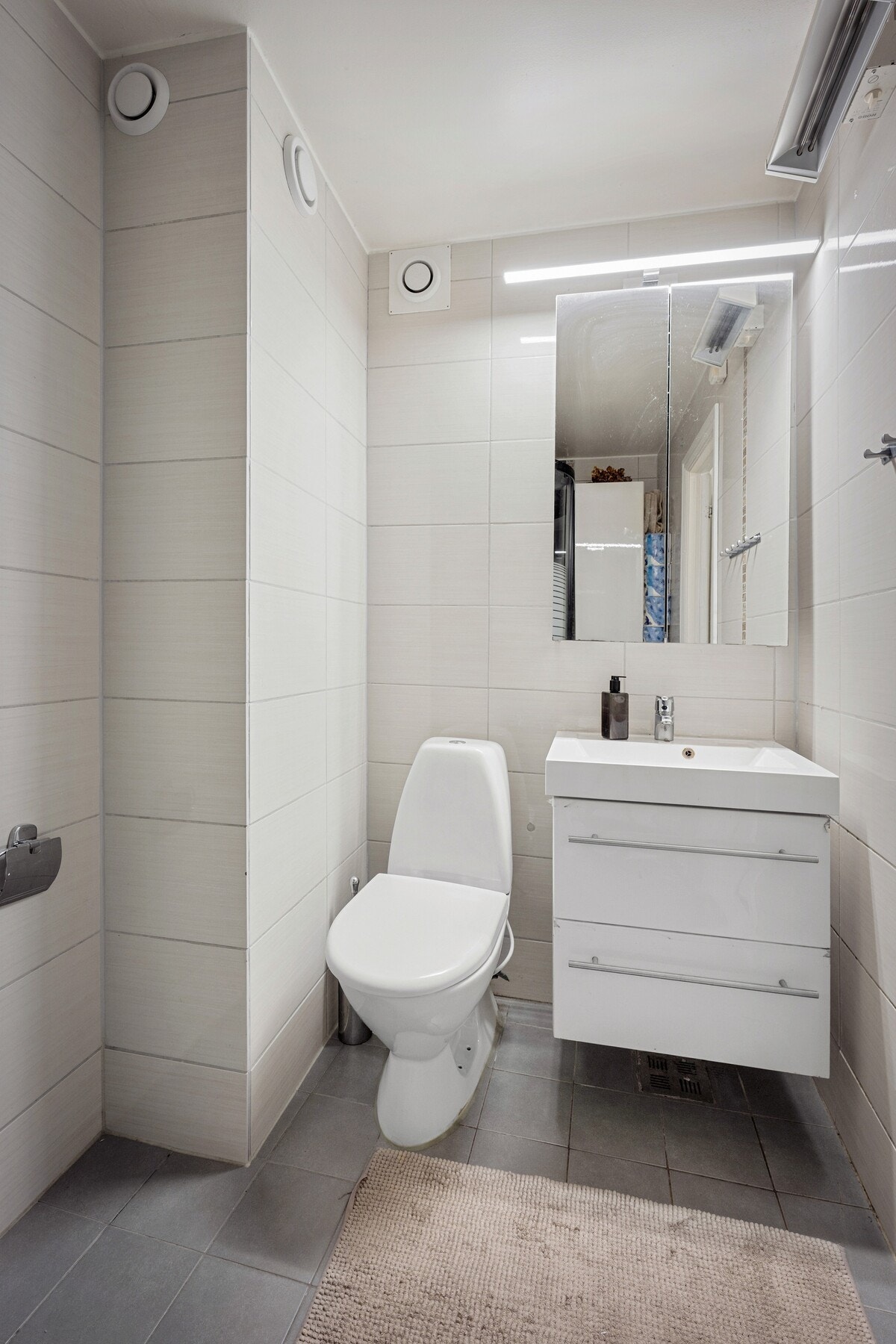 Badet er flislagt på gulv og vegger og ble ifølge eier oppgradert i 2015. Rommet er innredet med servant i benkeskap, speil med belysning, toalett og dusjkabinett. Galleribilde