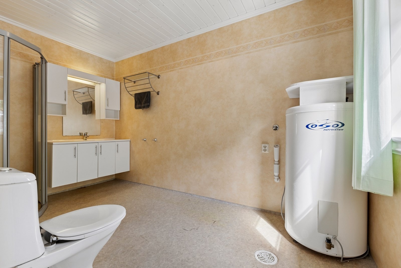Badet er innredet med vinylbelegg på gulv og vegger. Badet er ellers utstyrt med dusjhjørne, toalett og baderomsinnredning med god lagringsplass og nedfelt servant. I tillegg har badet opplegg for vaskemaskin og varmtvannsbereder. Galleribilde