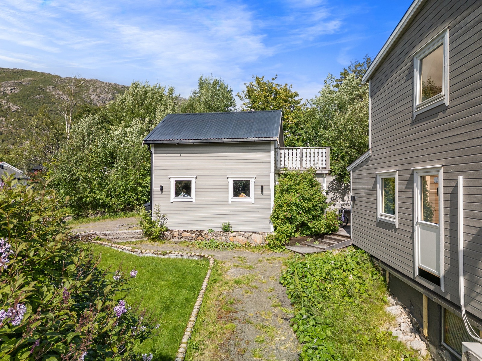 Inngang til kjelleretasje på fremsiden av bolig, og gårdsplass med plass til et par biler Galleribilde