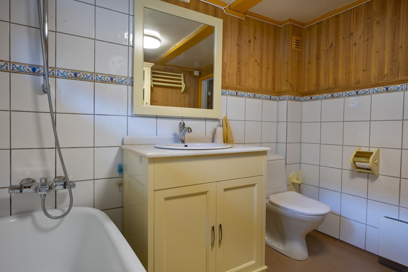 Badet har dels flislagte vegger og belegg på gulv, og rommet varmes opp med panelovn. Galleribilde