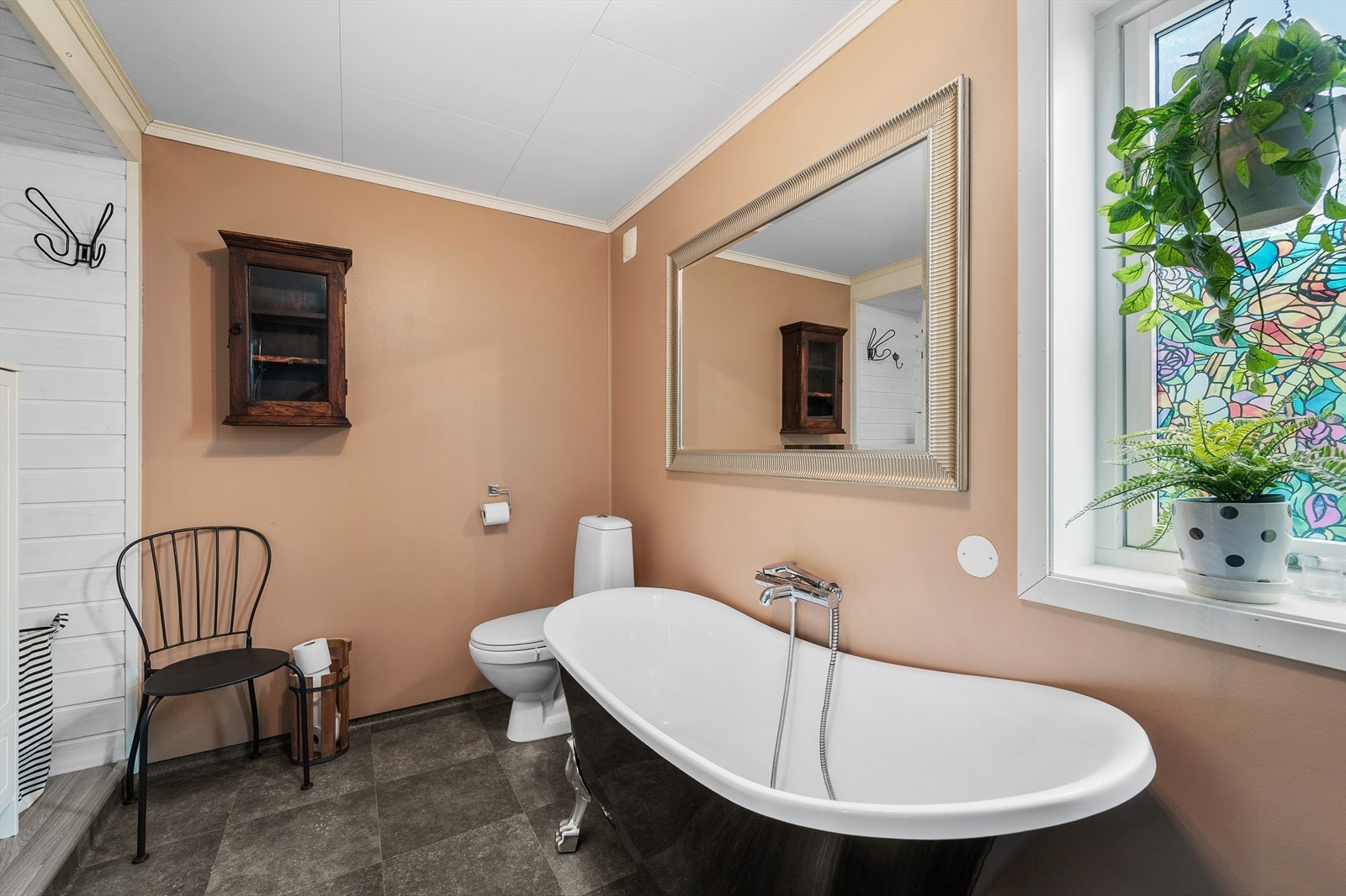 Badet er utstyrt med toalett, badekar, dusjvegg og servant med innredning. Galleribilde