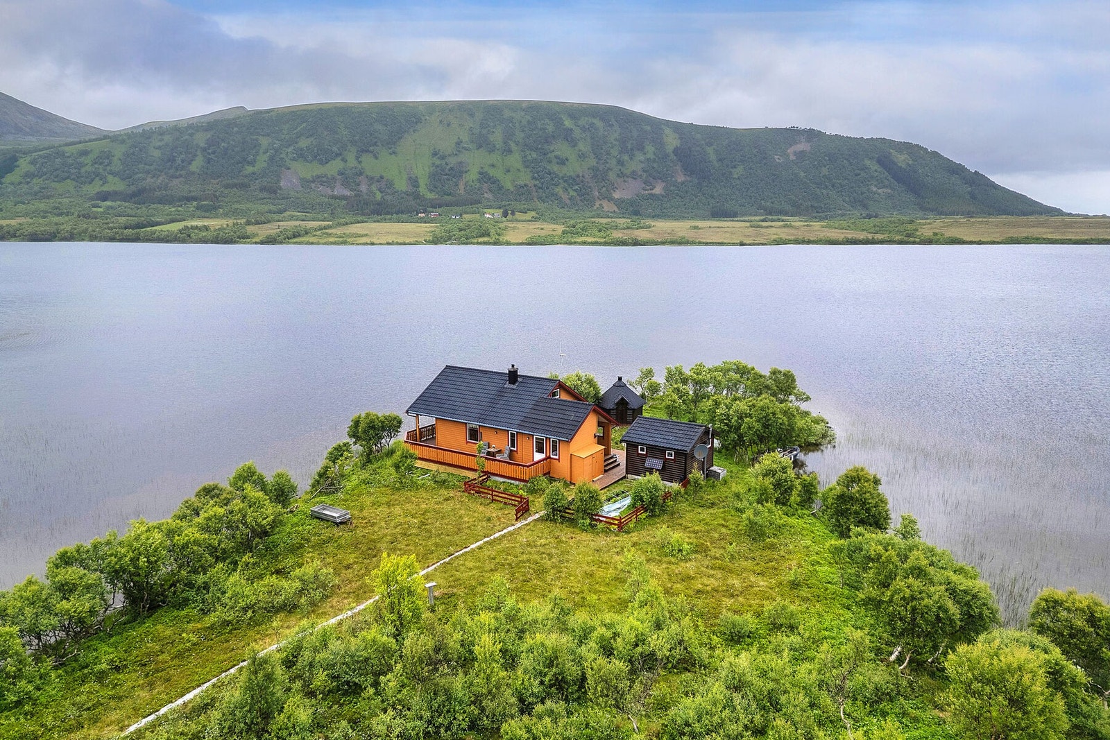 Hytta og uthusene er plassert harmonisk i det omkringliggende landskapet. Galleribilde