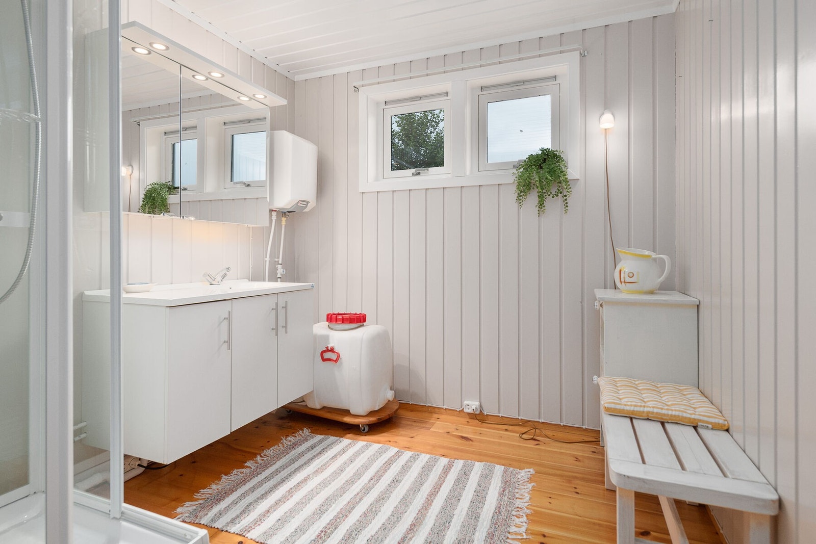 Badet har innredning med vask, speil og en vegghengt varmtvannsbereder. Vann hentes fra egen tank. Galleribilde