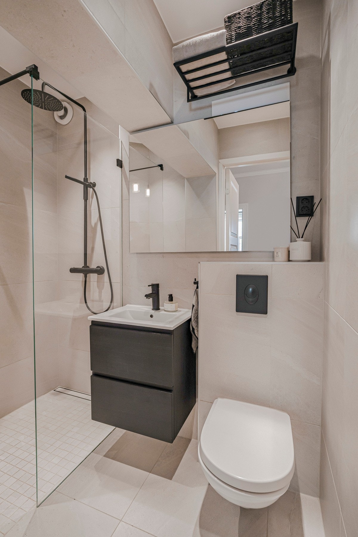 Delikat, flislagt bad med elektriske varmekabler i gulvet. Badet er innredet med vegghengt servantseksjon med skuffer, speilskap med integrert belysning, vegghengt toalett og dusjsone med nedsenket gulv, takdusj og glassvegg. Galleribilde