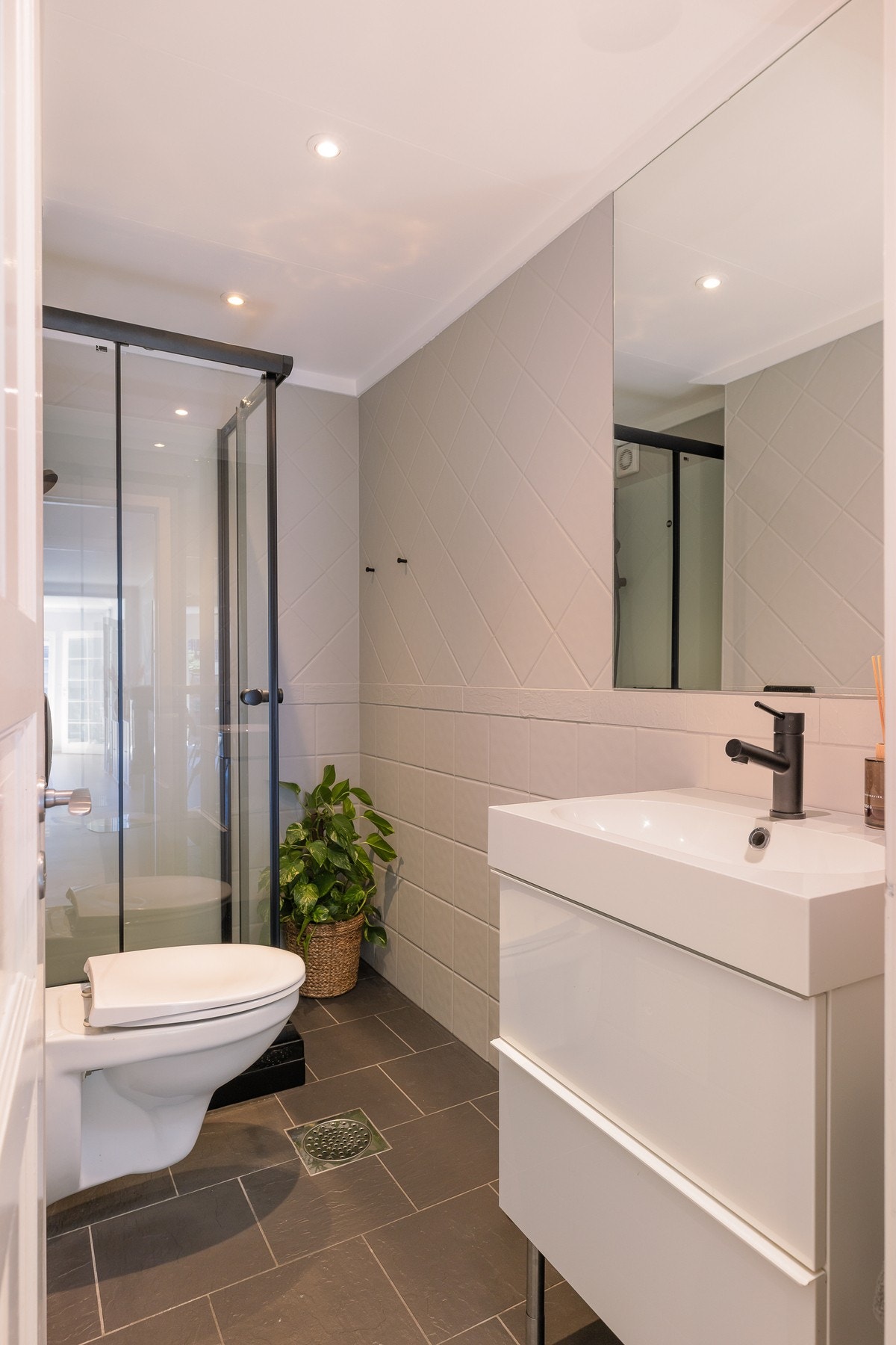 Badet er innredet med dusjkabinett, servant med innredning og vegghengt toalett. Galleribilde