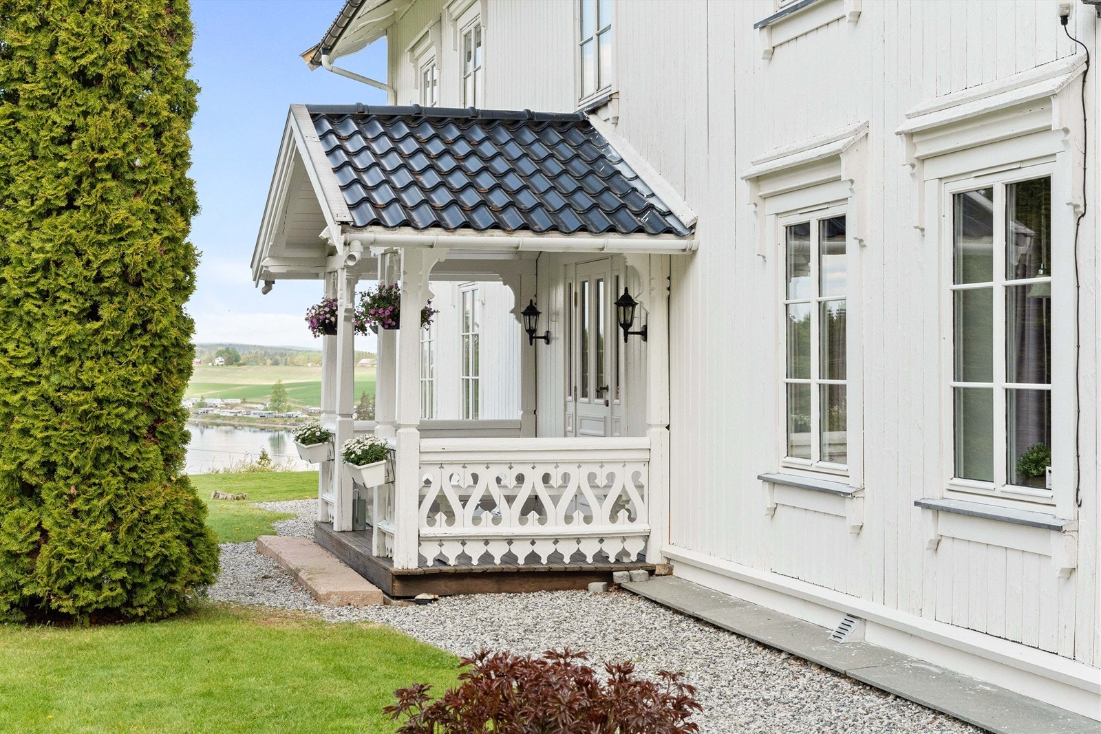 Overbygget inngangsparti med profilerte stolper og dekorativt rekkverk. Galleribilde