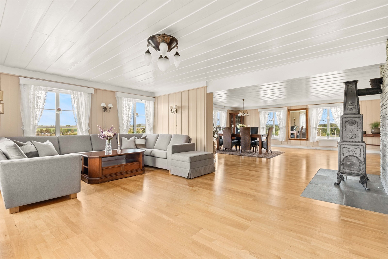 Åpen løsning mellom stue og spisestue, med en klassisk etasjeovn som et sentralt element. Galleribilde