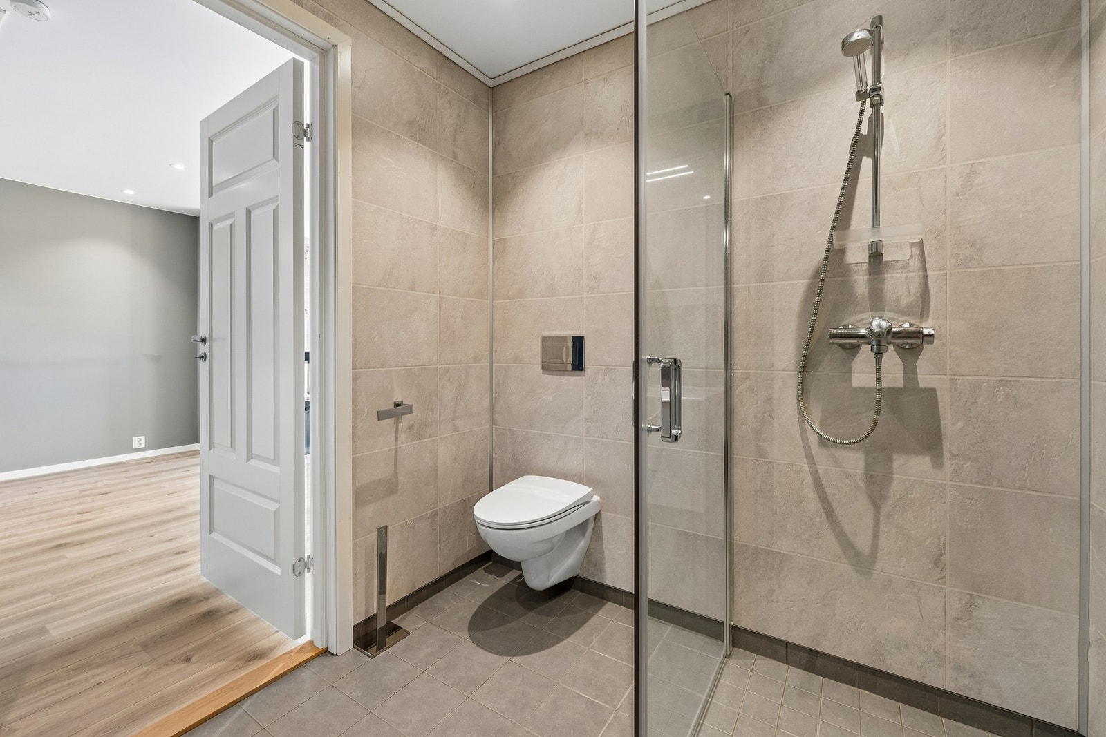 Badet har et vegghengt toalett, servant med overskap, og downlights og opplegg for oppvaskmaskin. Galleribilde