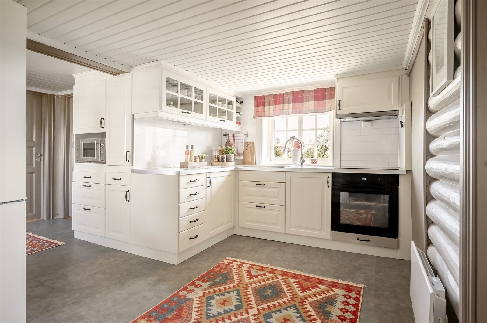 Innredningen har lyse profilerte fronter og laminert benkeplate med nedfelt oppvaskkum. Praktisk med lyse plater i benkeryggen og belysning under overskapene. Galleribilde