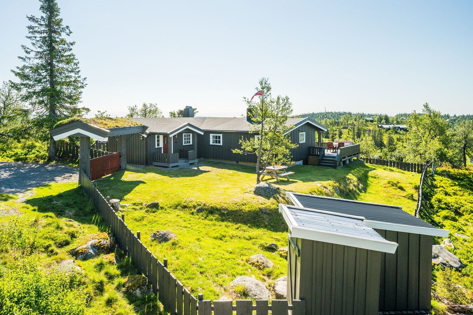 Hagen er pent opparbeidet med plen, beplantning, trær og en flaggstang. Galleribilde