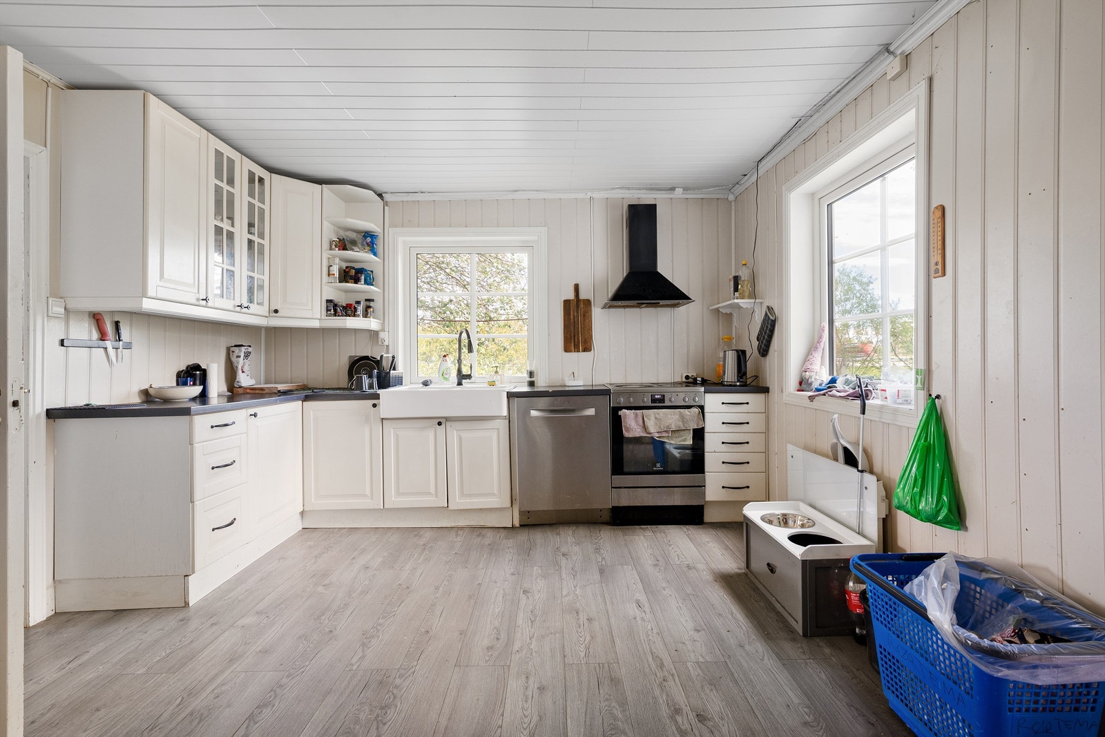 Innredning med profilerte fronter og laminert benkeplate med dobbel keramisk kum. Overskap med belysning, fritthengende ventilator med kullfilter og 3 doble stikkontakter. Hvitevarer som komfyr i nisje, innebygget oppvaskmaskin og kjøl/frys i nisje Galleribilde