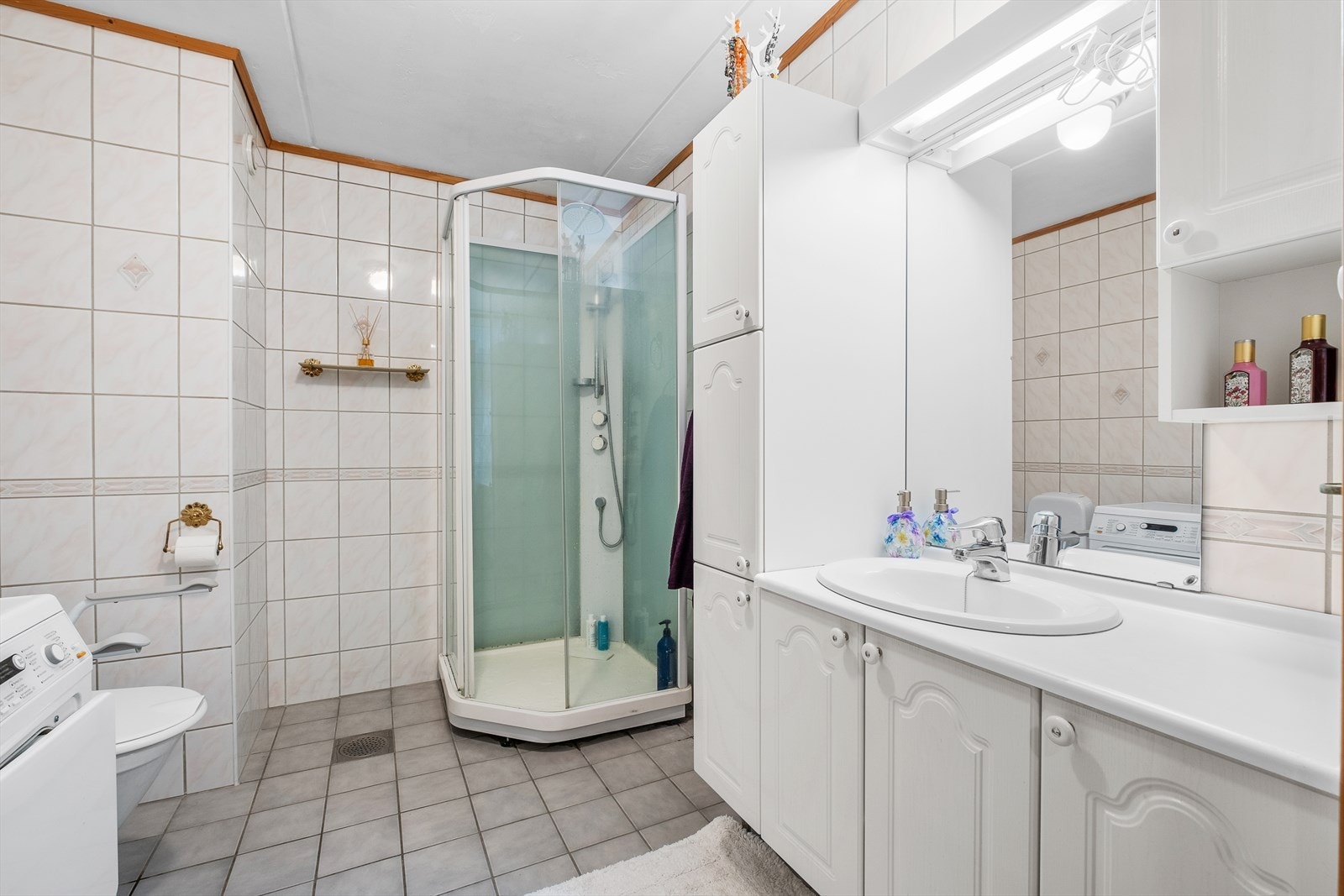 Badet er praktisk innredet med dusjkabinett, WC og servant med servantskap som gir god oppbevaringsplass. Galleribilde